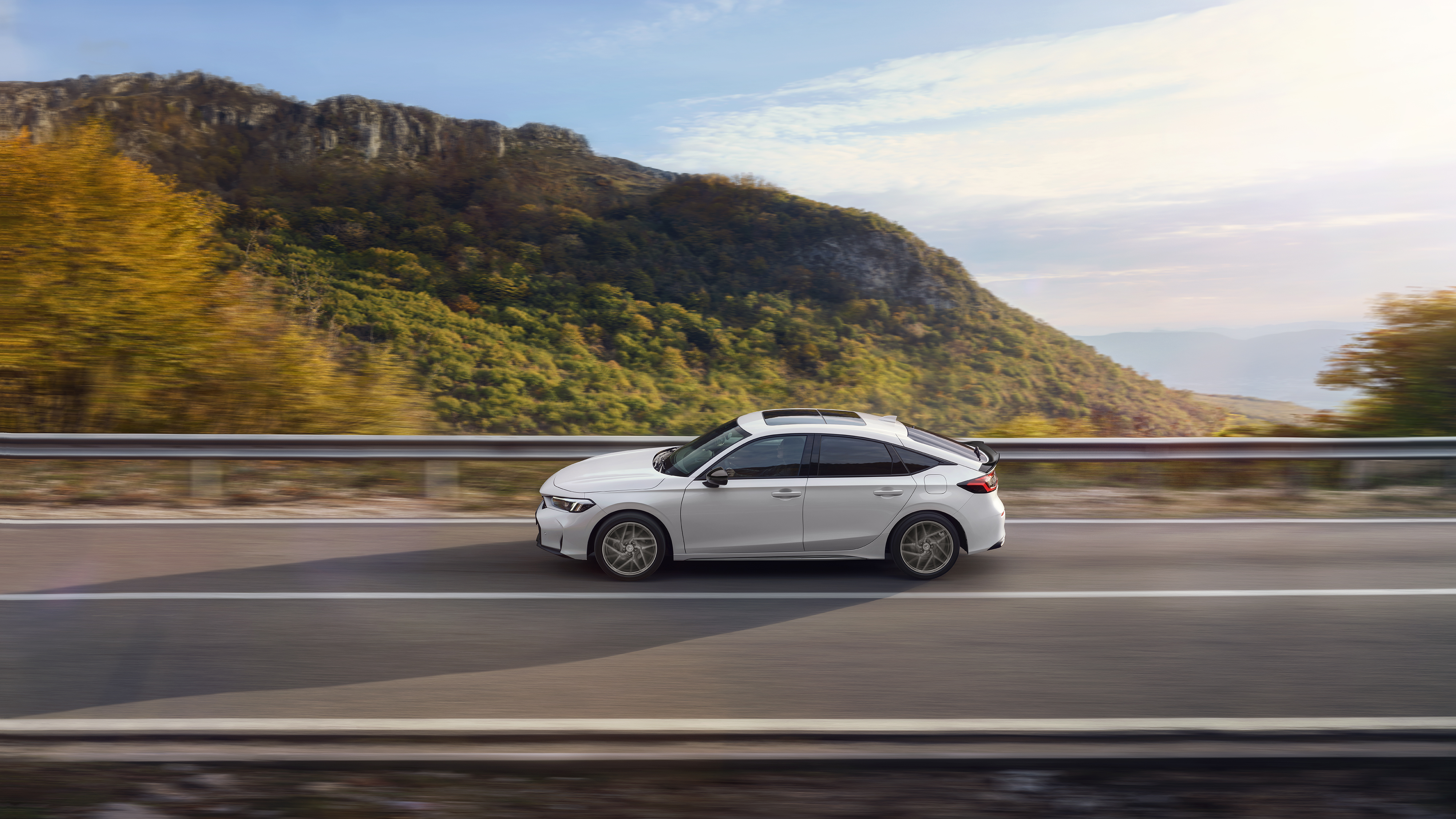 Honda Civic Hybrid v pohybe na diaľnici s malebným výhľadom.