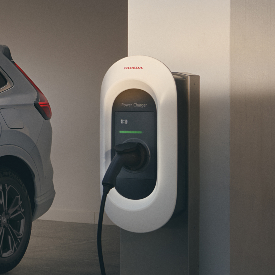 Trojštvrťový pohľad spredu na model Honda CR-V Hybrid pripojený k nabíjačke.