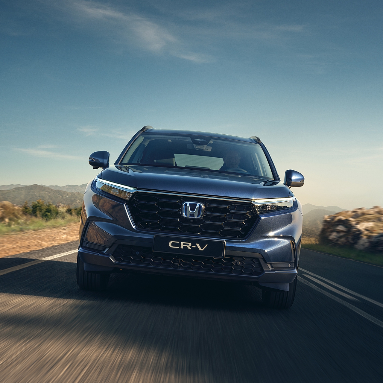 Pohľad spredu na model CR-V Hybrid pri jazde po ceste v horách.