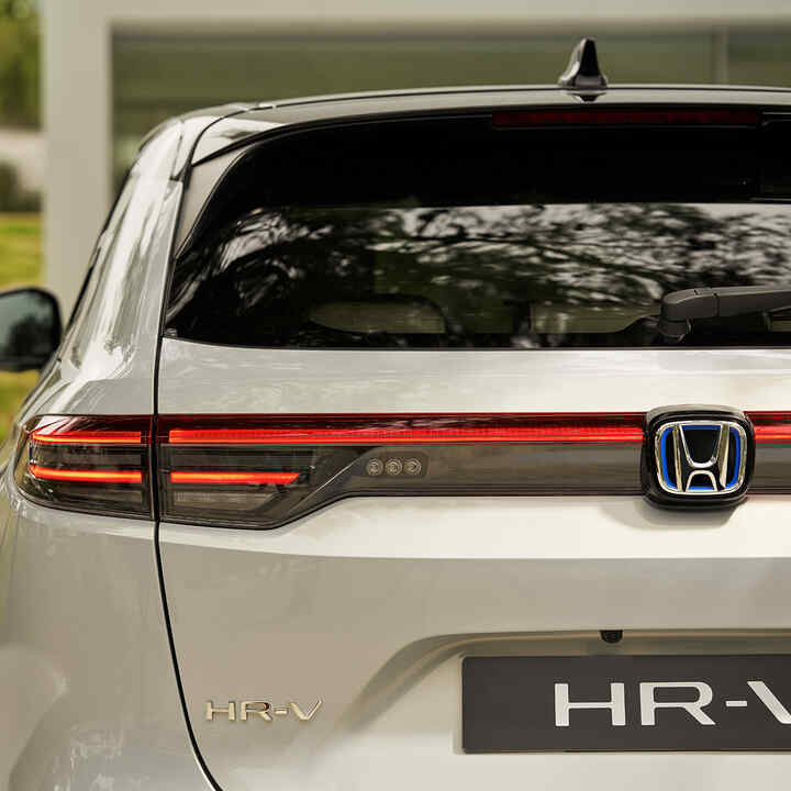 Pár kráča vedľa vozidla HR-V zaparkovaného pred budovou. 