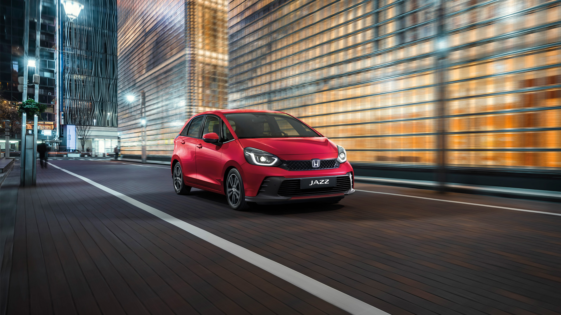 Trojštvrťový pohľad spredu na vozidlo Honda Jazz s mestským pozadím.