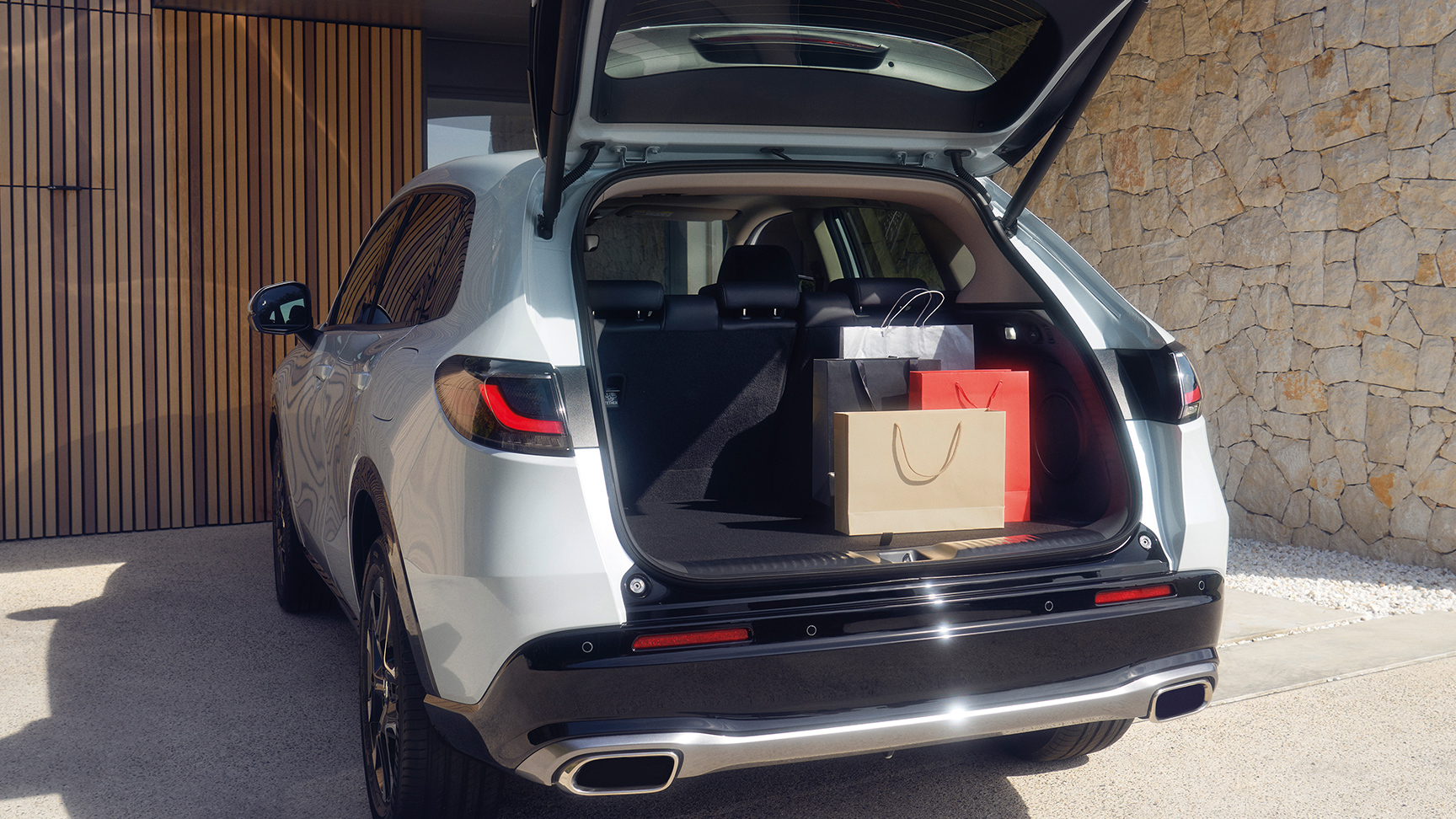 Biele vozidlo ZR-V na príjazdovej ceste s otvoreným batožinovým priestorom