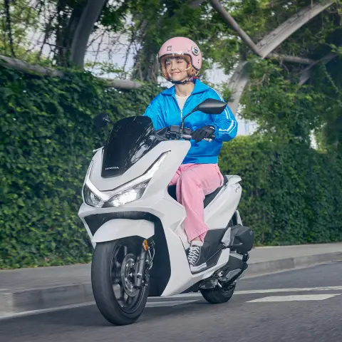 Figurant pri jazde na skútri PCX125 v meste.